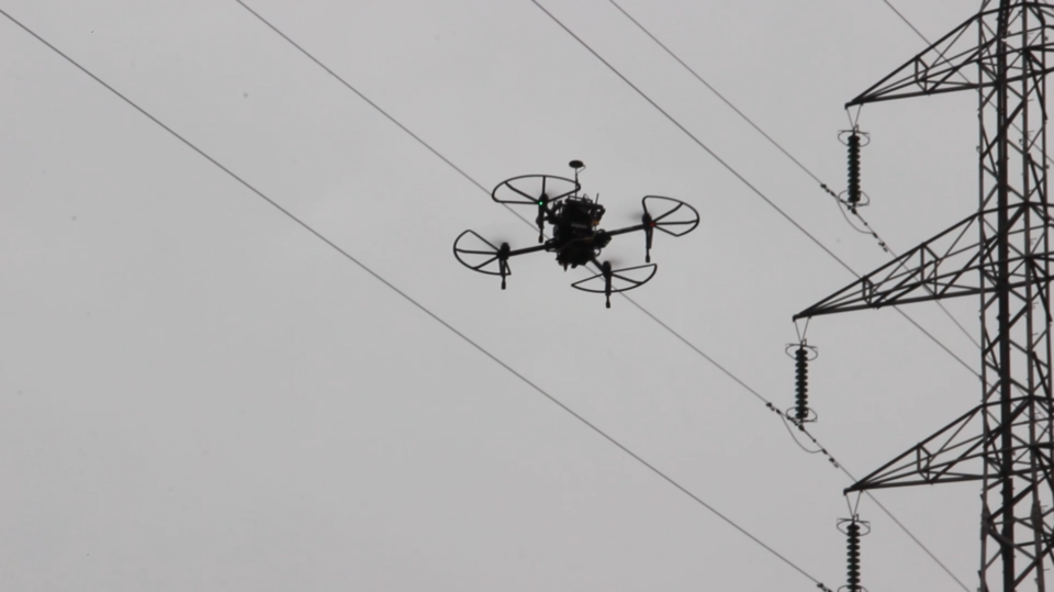 inspection drone flying beside a power-line pylon; user-provided case image